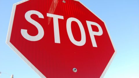 Stop sign image. White text on red octagon reads: STOP