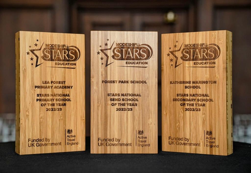 Three Modeshift STARS School Awards stand on table. Wooden awards with stars engraved.