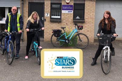 Three Brightwayz team members gather on bikes outside the Brightwayz office. Modeshift STARS Gold accreditation logo in the foreground.