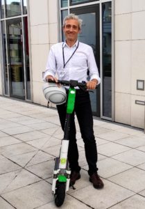Professor Ian Walker, Professor and Head of School of Psychology, Swansea University stands with electric scooter