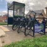 Three bikes parked by a shelter with sign that reads: Bike Hire