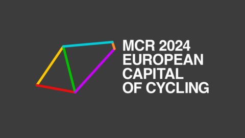 MCR 2024 European Capital of Cycling logo image. White text on grey background with multi-coloured prism shape