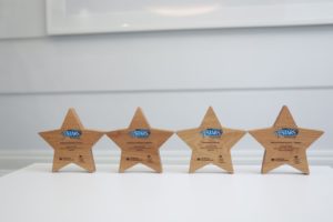 Four star shaped trophies with Modeshift STARS logo stand on white surface.