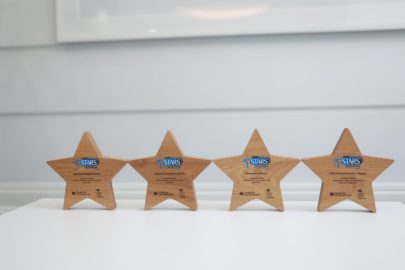 Four star shaped trophies with Modeshift STARS logo stand on white surface.