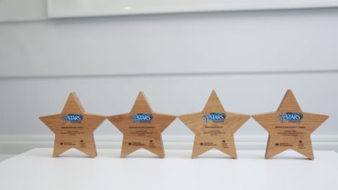 Four star shaped trophies with Modeshift STARS logo stand on white surface.