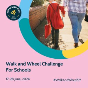 Test reads: Walk and Wheel Challenge for Schools. 17 - 28 June. #WalkandWheelSY Two people walk away from camera on a sunlit pavement, child wearing red school jumper on the left holds hands with a woman wearing jeans and a blue checked shirt.