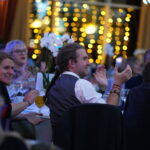 Modeshift 2023 Sustainable Travel Awards - crowd seated at tables, twinkling lights in background, applauding winners