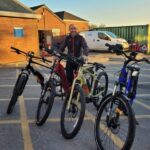 Man stands with four bikes in a row.