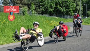 Three cyclists travel down a road. Two are adapted, non standard bikes. 