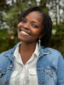 Woman smiles at camera. She wears blue denim jacket