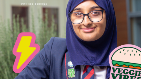 Girl wearing navy blue hijab, glasses, blue school blazer and black and red school tie sits with hands folded, smiling at camera. Text reads: Cut your Carbon. lightening bolt illustration to the right of her and illustration of a 'Veggie Vibes' burger to her right. Girl wearing navy blue hijab, glasses, blue school blazer and black and red school tie sits with hands folded, smiling at camera. Text reads: Cut your Carbon. lightening bolt illustration to the right of her and illustration of a 'Veggie Vibes' burger to her right. EchoSchools logo and Bupa Foundation logo