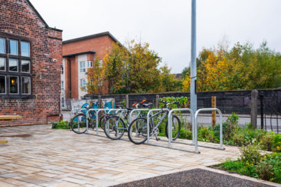 Cyclehoop credit. Three bikes stored in cycle parking area outside a red brick building.