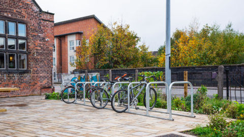 Cyclehoop credit. Three bikes stored in cycle parking area outside a red brick building.