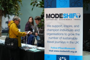 Woman collects her name badge from the registration desk at the Modeshift Convention.