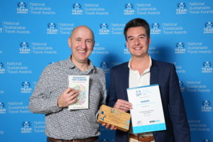 Two men stand together, holding their awards high at the national sustainable travel awards, symbolising their success and recognition.