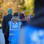 A group of people walking wrapped up in winter clothes, some wearing Team Modeshift blue high vis vests