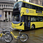 Credit: DfT Yellow double decked bus with two yellow e-bikes parked in front.