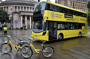 Credit: DfT Yellow double decked bus with two yellow e-bikes parked in front.