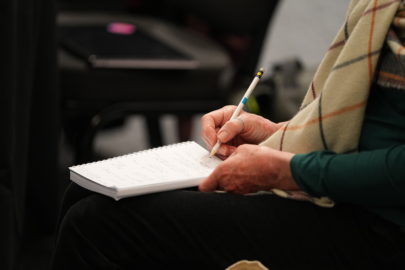 Close up image of woman's hands as she holds a pen to write on a note pad.