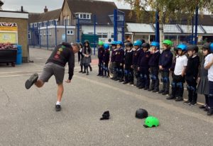 Scoot Fit training. School children lined up in school playground taking part in Scoot Fit training. Trainer demonstrates in school playground