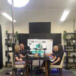 A group of people seated around a table in a recording studio environment