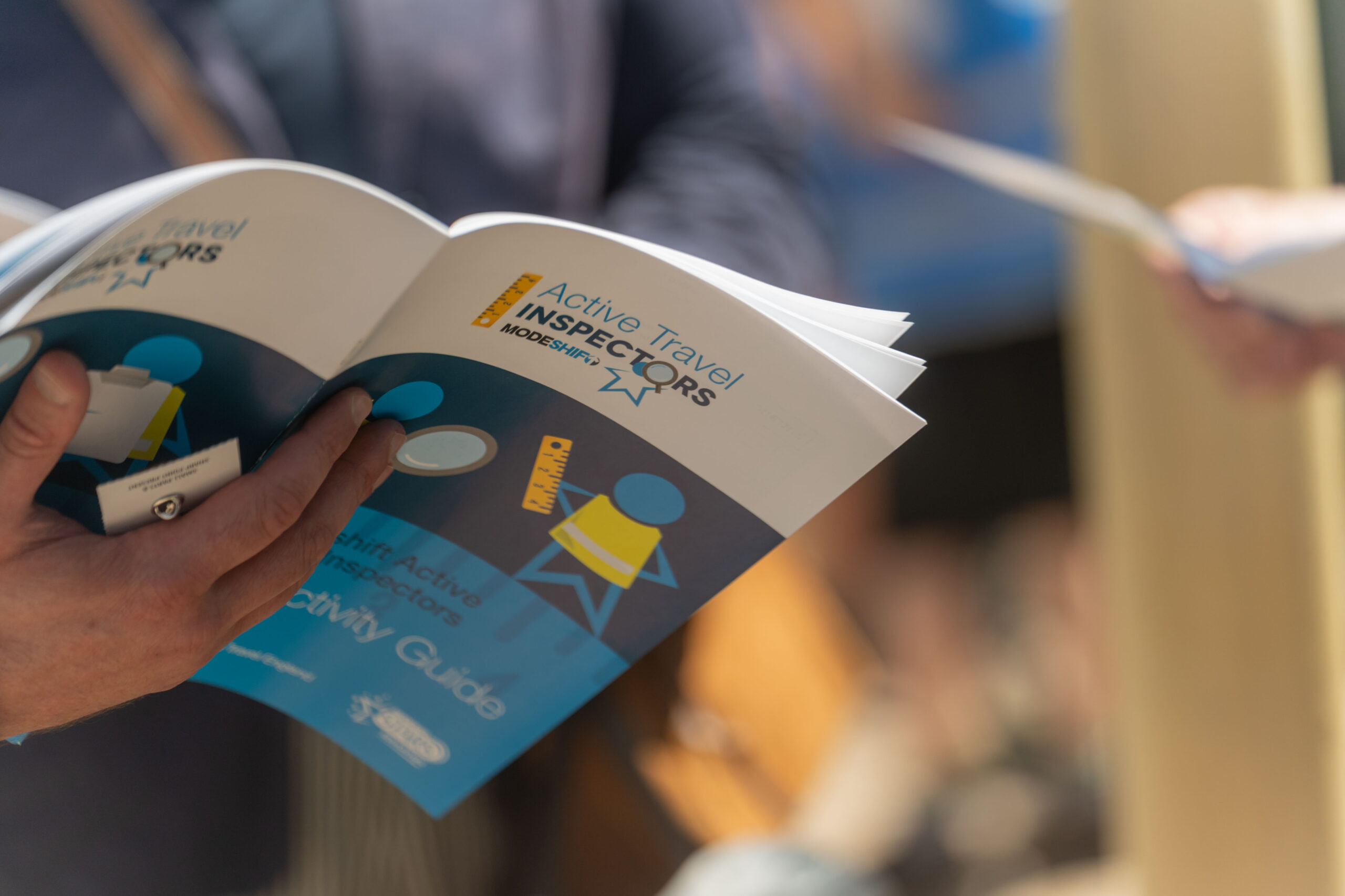 Childs hand holding an 'Active Travel Inspectors' booklet.