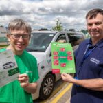 Two people stand outdoors holding LocalGo travel brochures in front of a white vehicle with LocalGo branding.