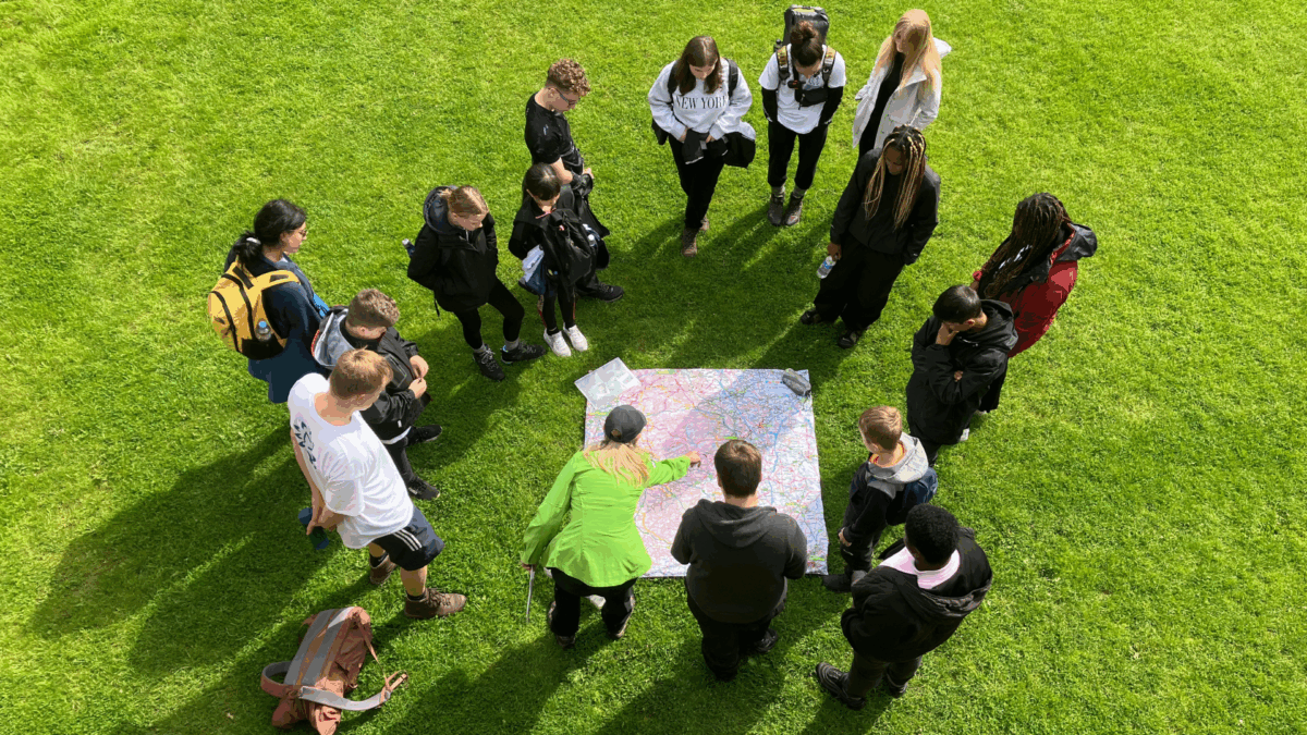 people stood on grass looking at a large map