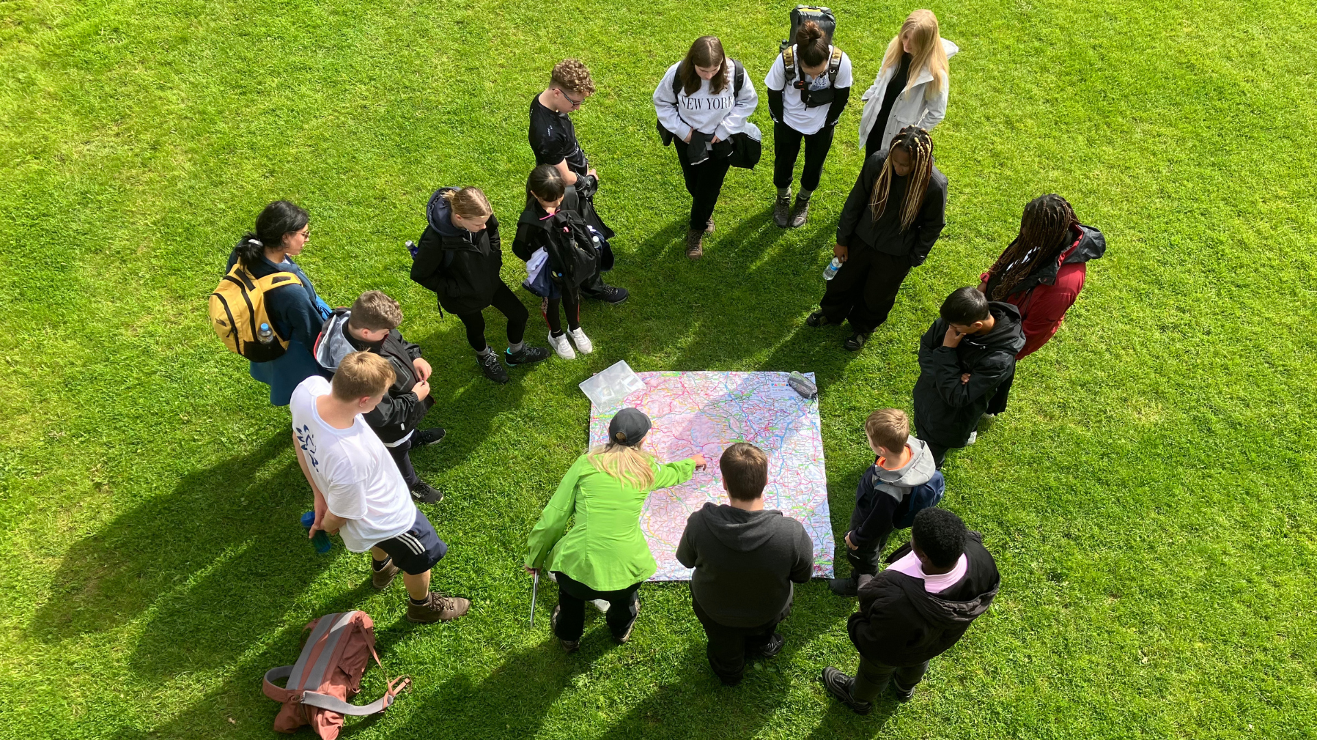 people stood on grass looking at a large map