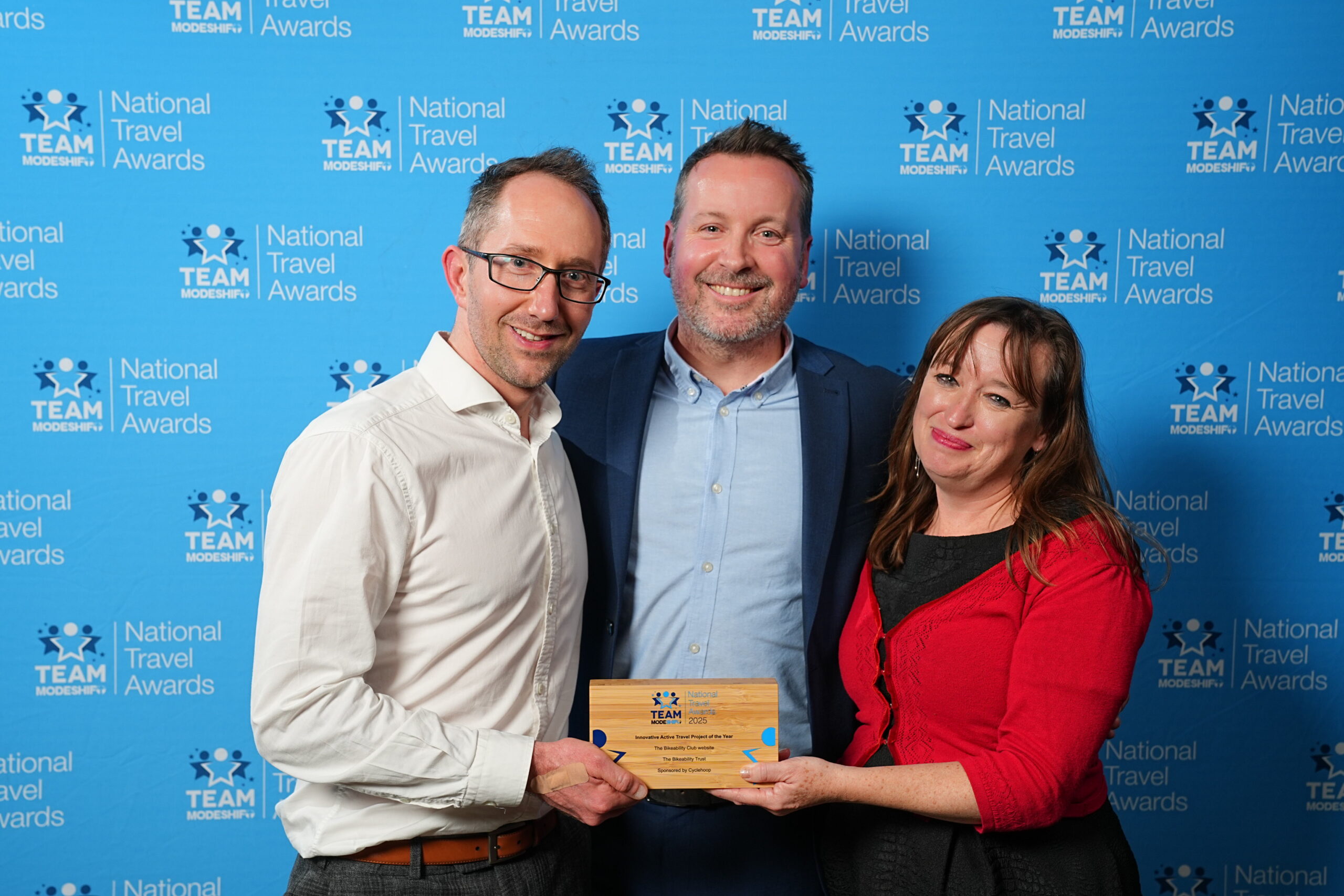 Innovative Active Travel Project of the Year Sponsored by Cyclehoop Bikeability Club website The Bikeability Trust Group of people stand smiling, central figures holding their TeamModeshift Award