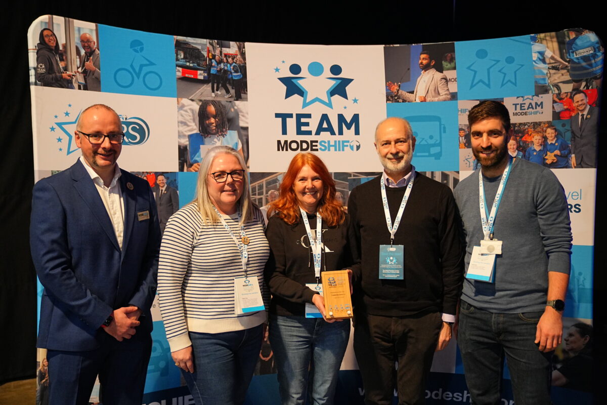 Nick Butler, Clare Crisp, Alison Barraclough, Fabian Hamilton MP, Ewhen Chymera stand in front of a Modeshift branded display stand.