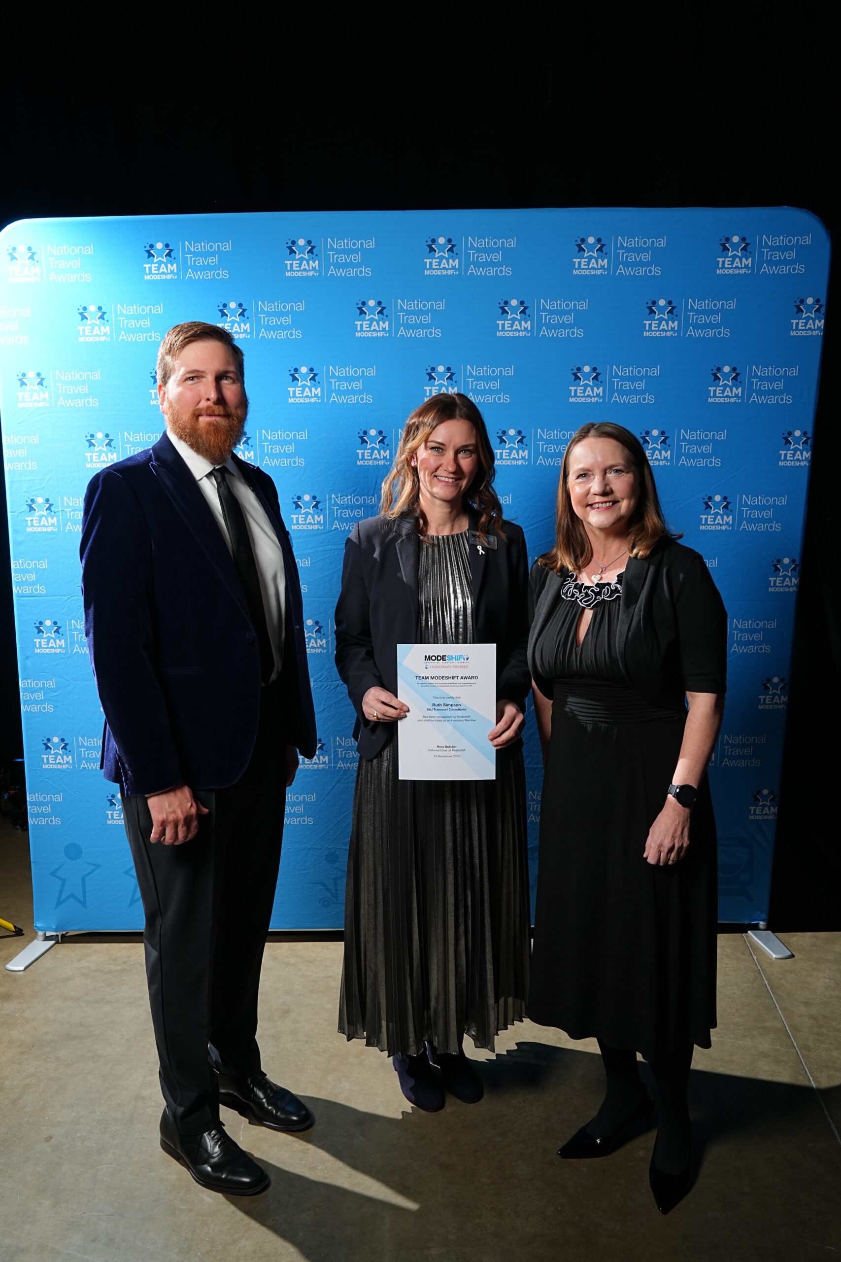 Ruth Simpson, SAJ Transport Consultants poses with Honorary Member Certificate, two people smile at camera either side.