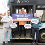 Three men stand in front of an Arriva bus holding signs promoting Hugglescote Grange & Swinfen Vale with Harworth and Bircotes stops.