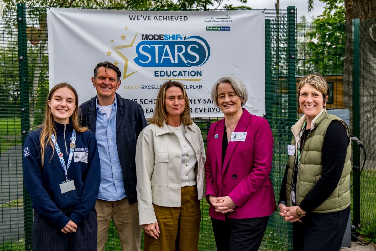 Five people stand in front of a banner that reads "WE'VE ACHIEVED MODESHIFT STARS EDUCATION GOLD: EXCELLENCE IN SCHOOL JOURNEY SAFETY FOR EVERYONE."