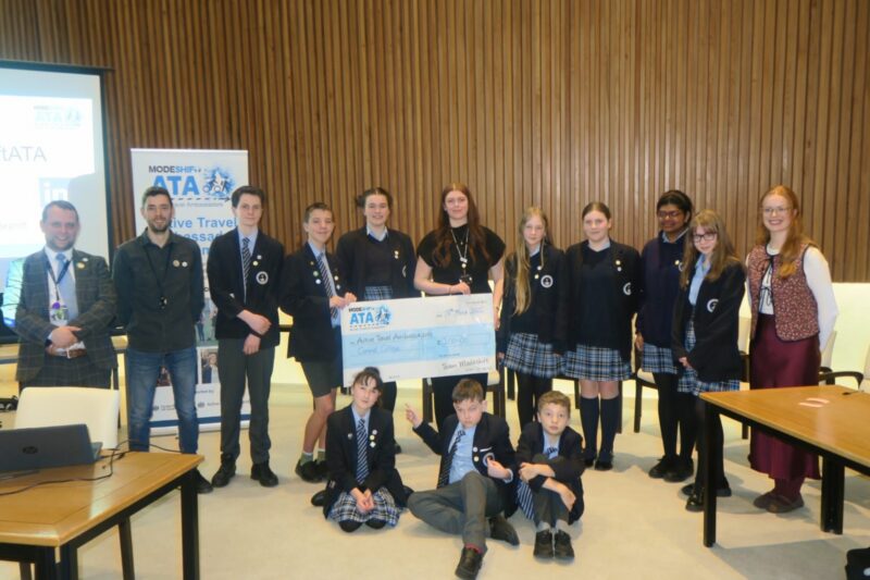 Students in school uniform pose with a large cheque for the Active Travel Ambassadors Campaign funding awarded at the Campaign Junction event.