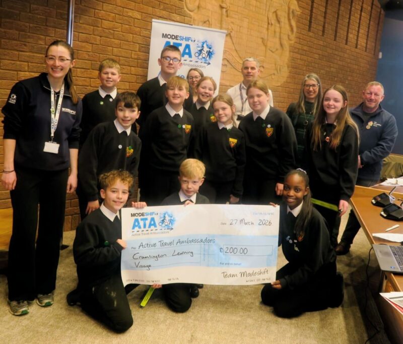 Students in school uniform pose with a large cheque for the Active Travel Ambassadors Campaign funding awarded at the Campaign Junction event.