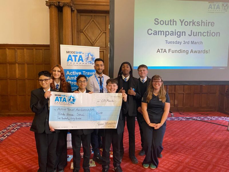 Students in school uniform pose with a large cheque for the Active Travel Ambassadors Campaign funding awarded at the Campaign Junction event.