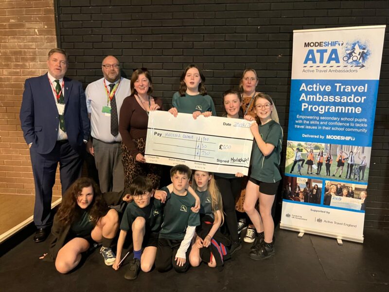 Students in school uniform pose with a large cheque for the Active Travel Ambassadors Campaign funding awarded at the Campaign Junction event.