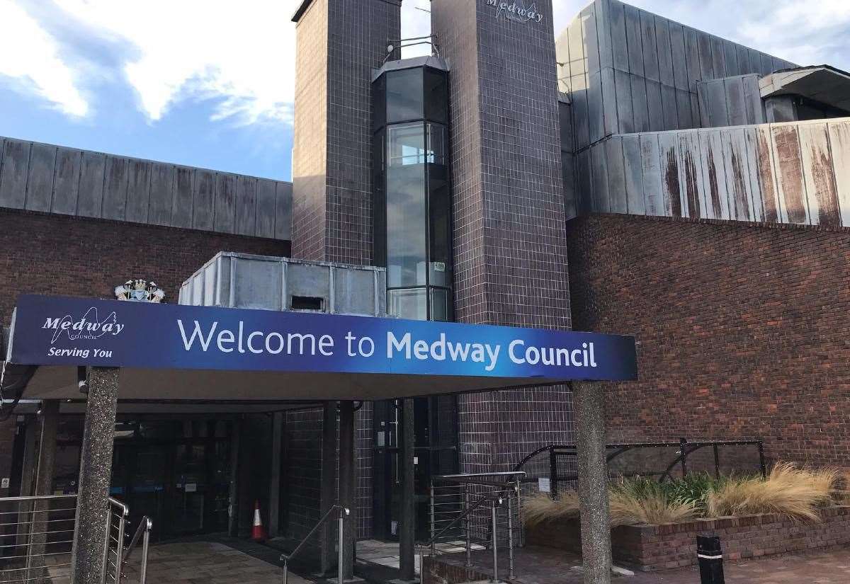 A blue banner over an entrance reads "Welcome to Medway Council" with the Medway Council logo. The building behind is made of brick and metal panels with a glass elevator shaft visible. Medway Council - Leading by Example with a Workplace Travel Plan