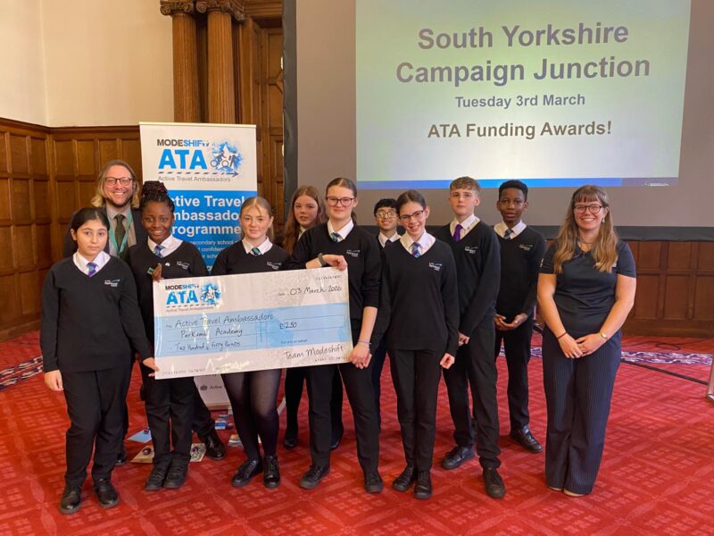 Students in school uniform pose with a large cheque for the Active Travel Ambassadors Campaign funding awarded at the Campaign Junction event.