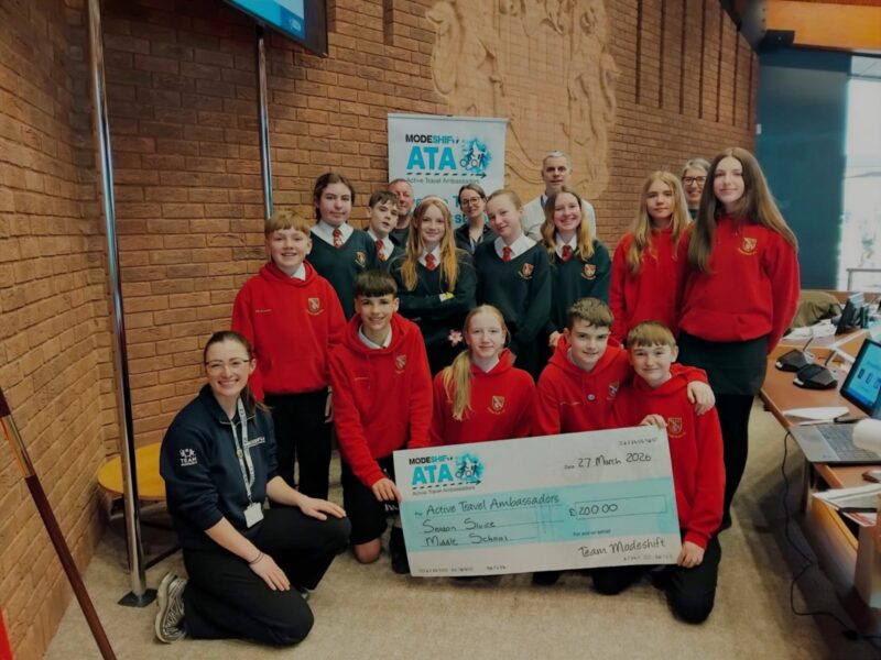 Students in school uniform pose with a large cheque for the Active Travel Ambassadors Campaign funding awarded at the Campaign Junction event.